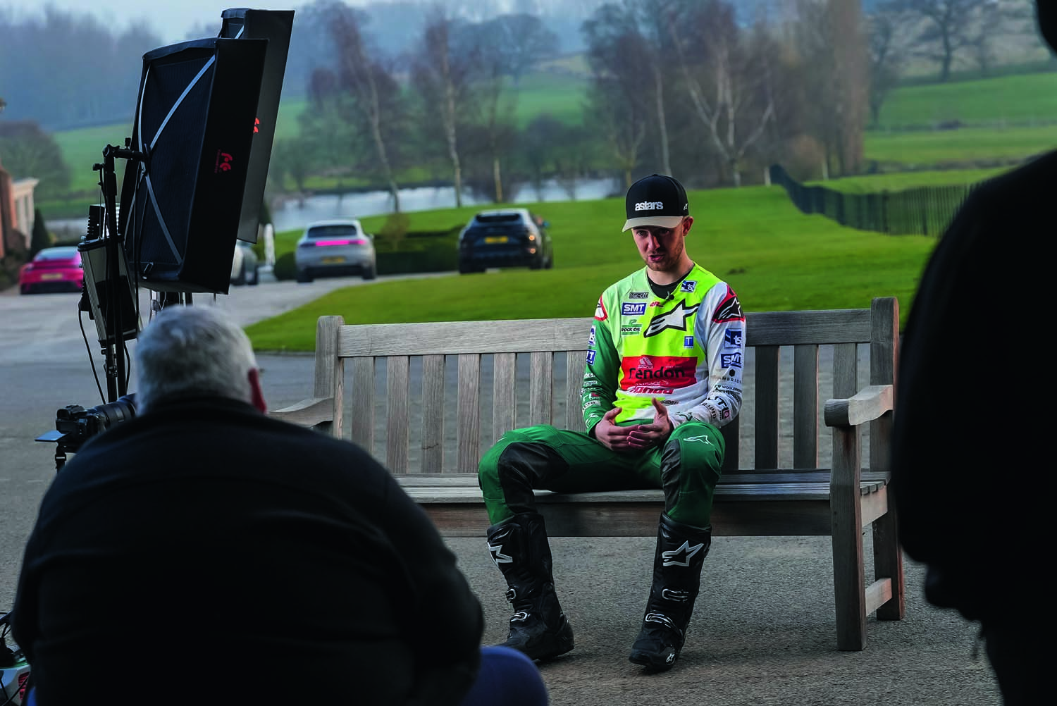 Man interviewing motocross rider on park bench
